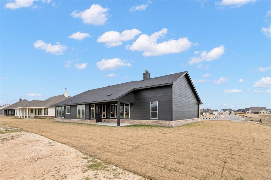 Rear view of house with a chimney, a patio, and a lawn