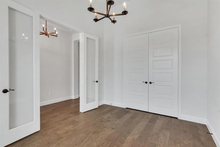 Unfurnished bedroom featuring a closet, an inviting chandelier, and hardwood / wood-style floors