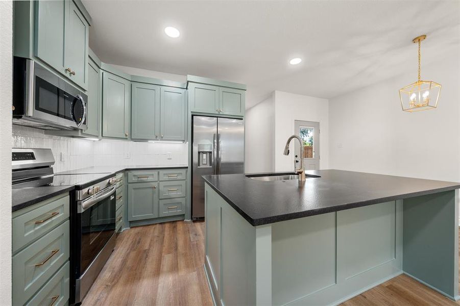 Kitchen featuring stainless steel appliances, tasteful backsplash, dark wood finished floors, a kitchen island with sink, and recessed lighting Kitchen featuring stainless steel appliances, tasteful backsplash, dark wood finished floors, a kitchen island with sink, and recessed lighting