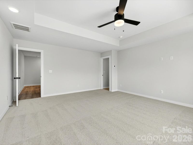 Primary bedroom features tray ceiling, 3 large windows allow the room to be flooded with natural light while allowing views of private wooded backyard.