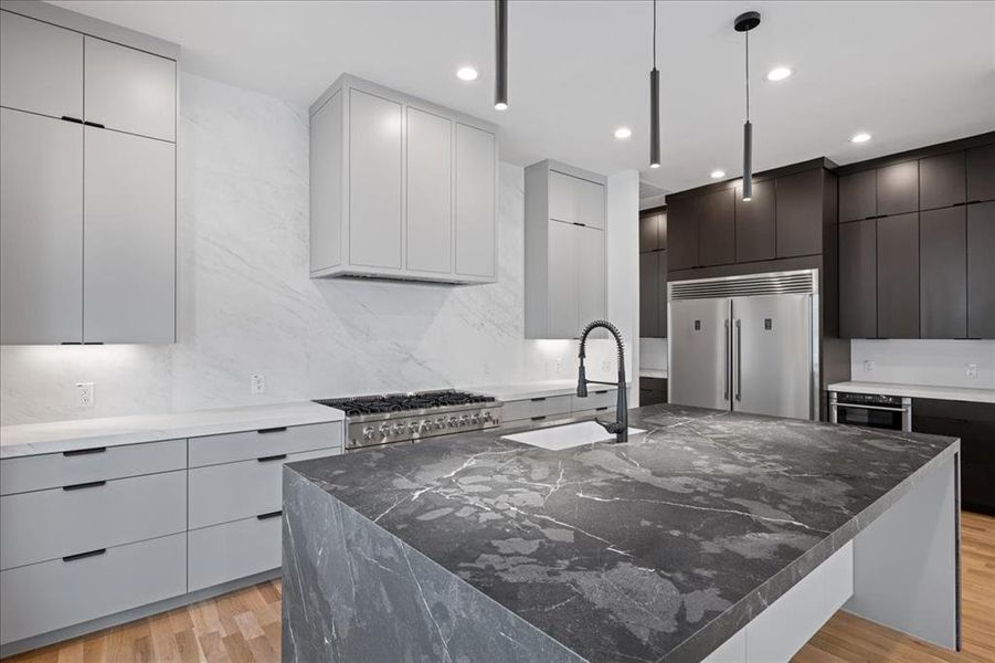 Kitchen featuring modern cabinets, extra large island, light wood-type flooring, an island with sink, dark stone counters, and recessed lighting Kitchen featuring modern cabinets, extra large island, light wood-type flooring, an island with sink, dark stone counters, and recessed lighting