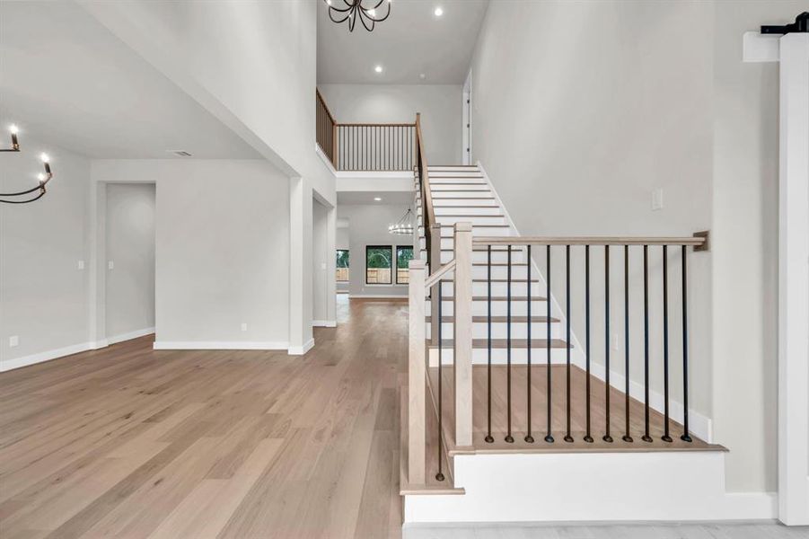 Open entry with wood flooring from the foyer through to the dining, family room and kitchen beyond. The staircase has wrought iron spindles and wood treads.