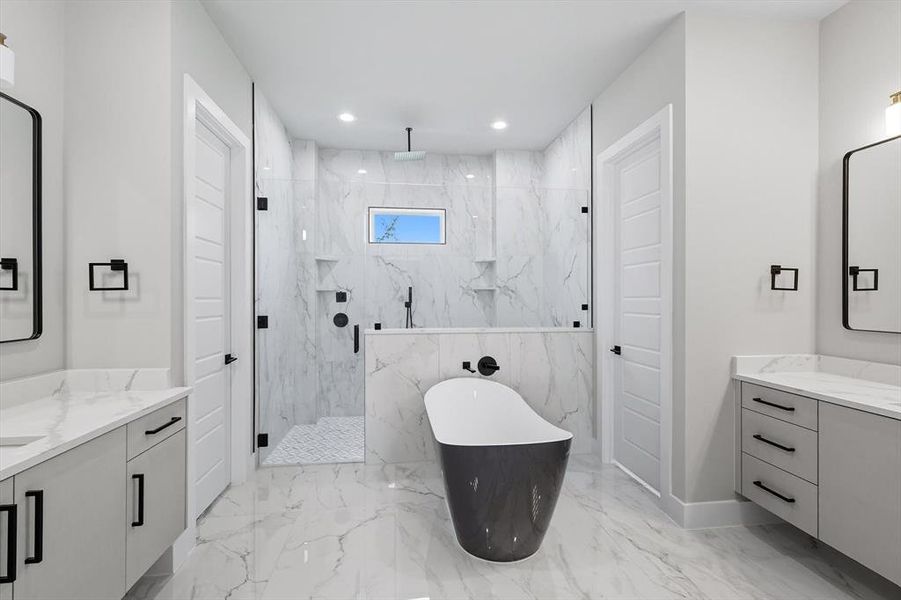 Bathroom featuring a marble finish shower, a freestanding bath, two vanities, recessed lighting, and light marble finish flooring