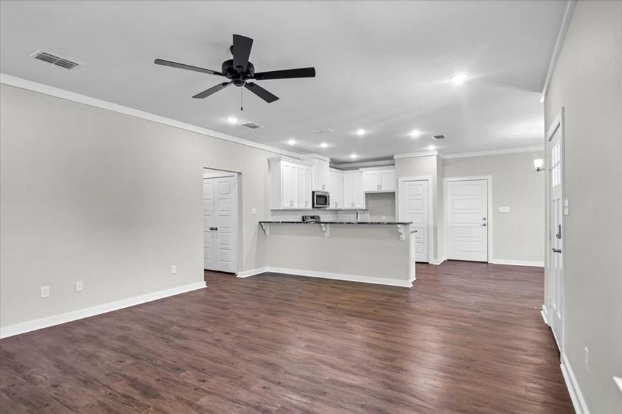 Unfurnished living room with ornamental molding, recessed lighting, ceiling fan, baseboards, and dark wood finished floors