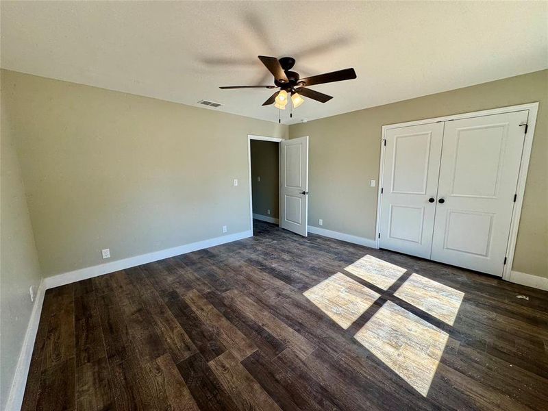 Unfurnished bedroom with dark wood finished floors, a closet, and a ceiling fan