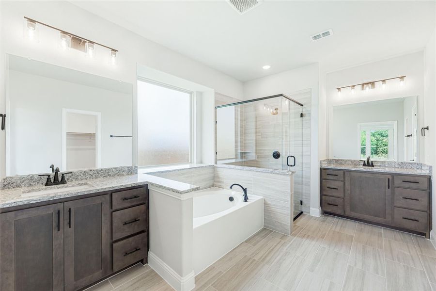 Master bathroom with dual vanities, soaking tub, glass walk-in shower, and dark wood cabinets with granite countertops Master bathroom with dual vanities, soaking tub, glass walk-in shower, and dark wood cabinets with granite countertops