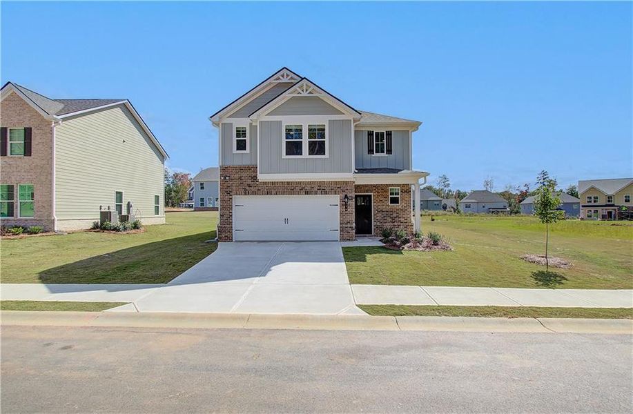 View of front of home featuring a front yard, central AC, and a garage