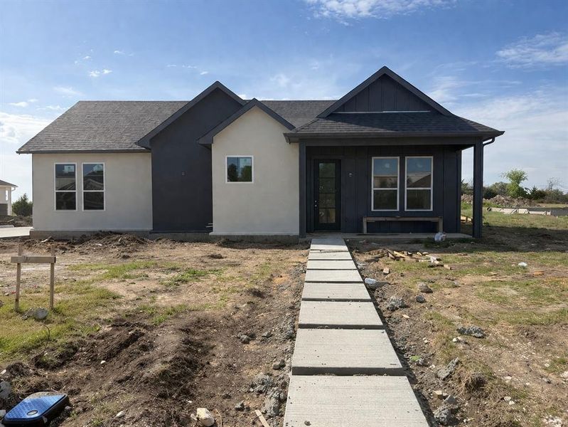 View of front of house featuring a shingled roof, board and batten siding, a porch, and stucco siding