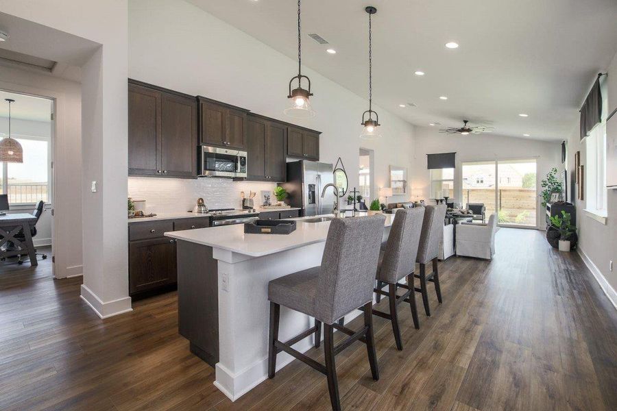 Kitchen featuring visible vents, dark brown cabinetry, a breakfast bar, dark wood-style floors, and stainless steel appliances