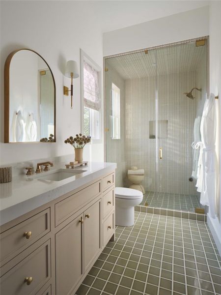 Vanity lights in hand rubbed antique brass with saddle leather complement this serene bath.