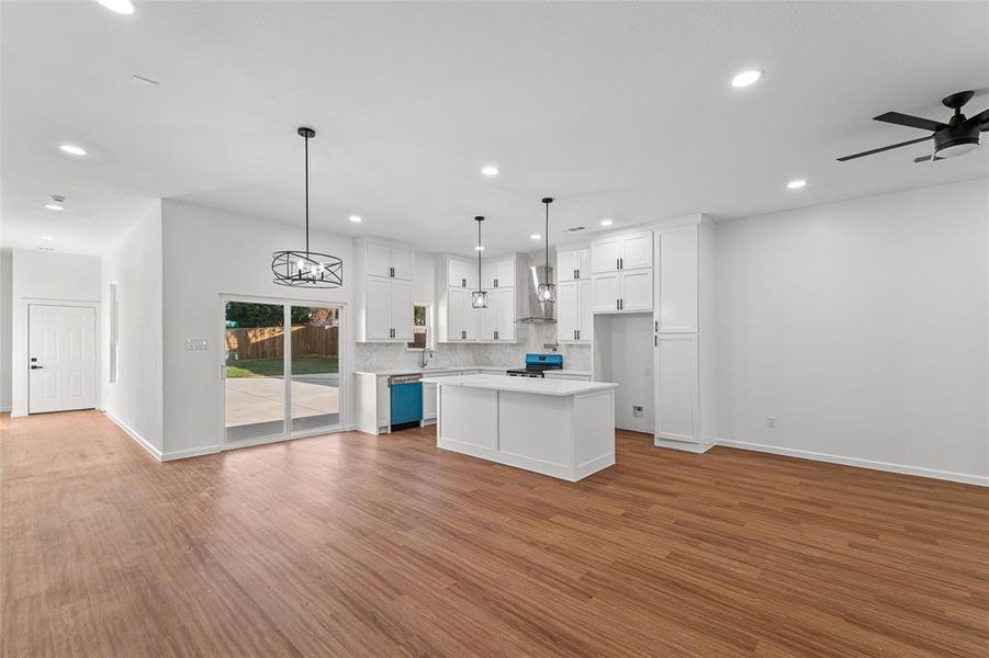 Kitchen with open floor plan, a kitchen island, white cabinetry, pendant lighting, and recessed lighting
