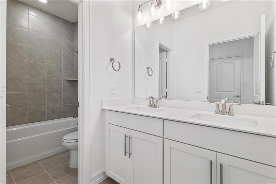 Bathroom featuring light tile patterned floors, double vanity, and bathing tub / shower combination