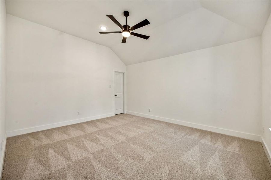 Spare room featuring lofted ceiling, light colored carpet, and ceiling fan