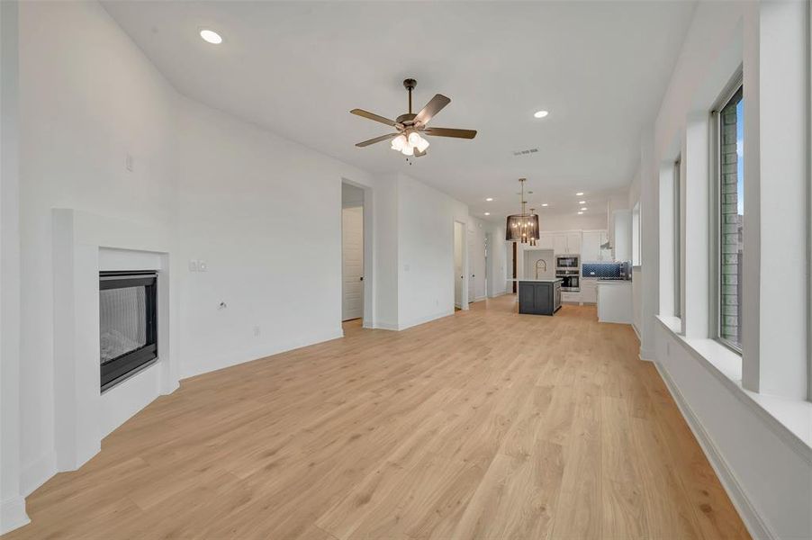 Expansive open-concept room featuring wood-finish flooring, a contemporary fireplace, and recessed lighting