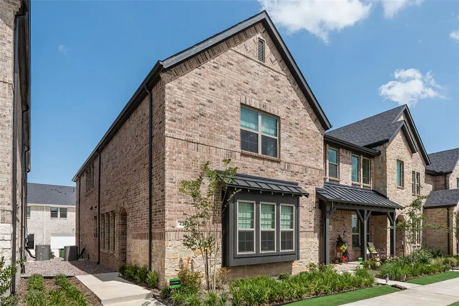 Brick exterior featuring a gabled roofline, dark-framed windows, and a bay window with a metal awning Brick exterior featuring a gabled roofline, dark-framed windows, and a bay window with a metal awning