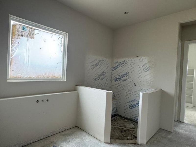 Unfinished bathroom with a window, recessed ceiling lighting, and a shower enclosure framed for installation