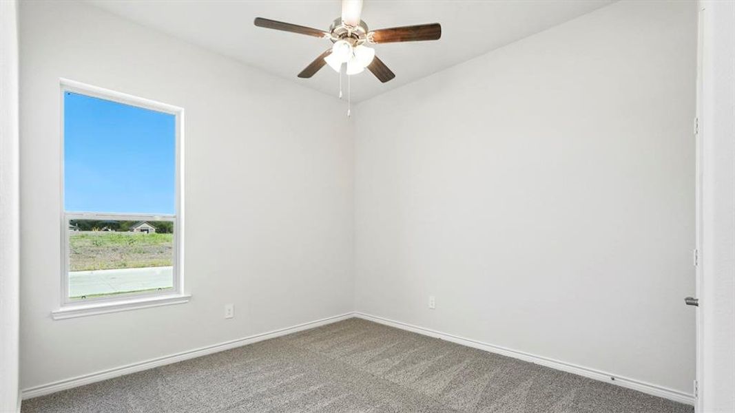 Carpeted spare room with baseboards and a ceiling fan