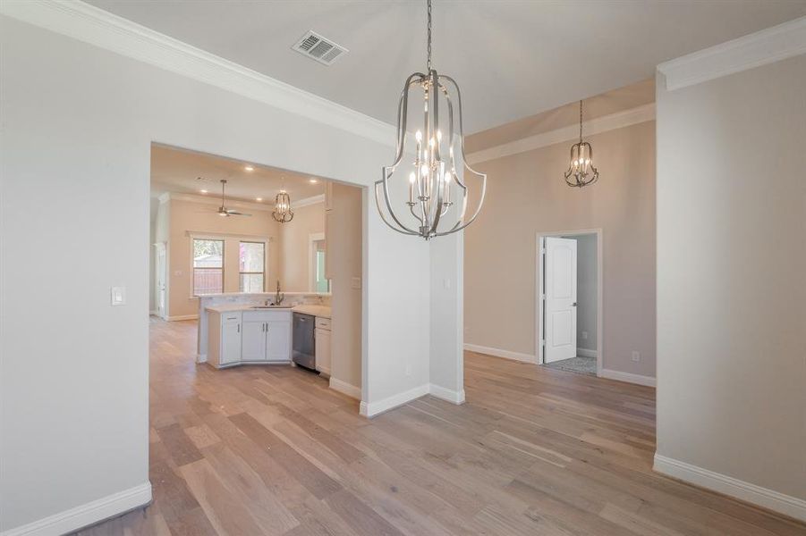 Unfurnished dining area featuring ceiling fan, sink, french doors, light wood-type flooring, and ornamental molding