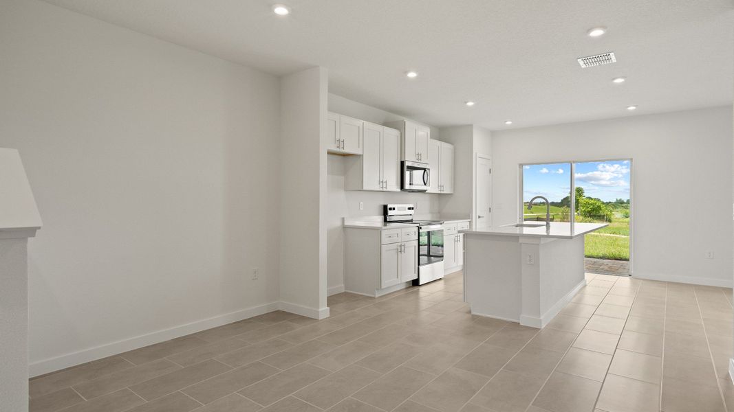 Bright and open-concept kitchen flows into great room with sleek finishes and beautiful backyard views
