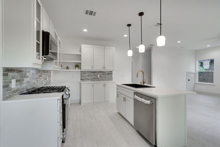 Kitchen featuring sink, stainless steel appliances, decorative backsplash, and white cabinets