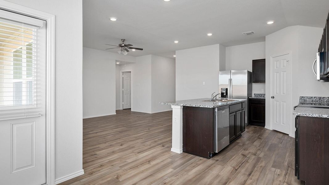 Kitchen with light stone counters, recessed lighting, light wood-style flooring, a center island with sink, and ceiling fan