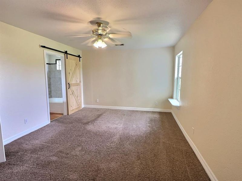Carpeted  bedroom featuring a ceiling fan and a barn door
