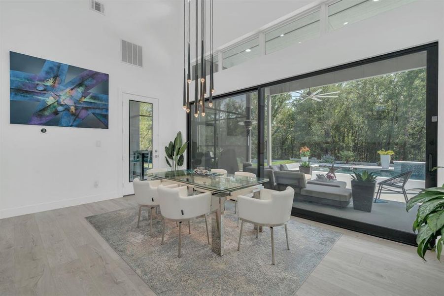 Dining area featuring a towering ceiling and light wood-style flooring