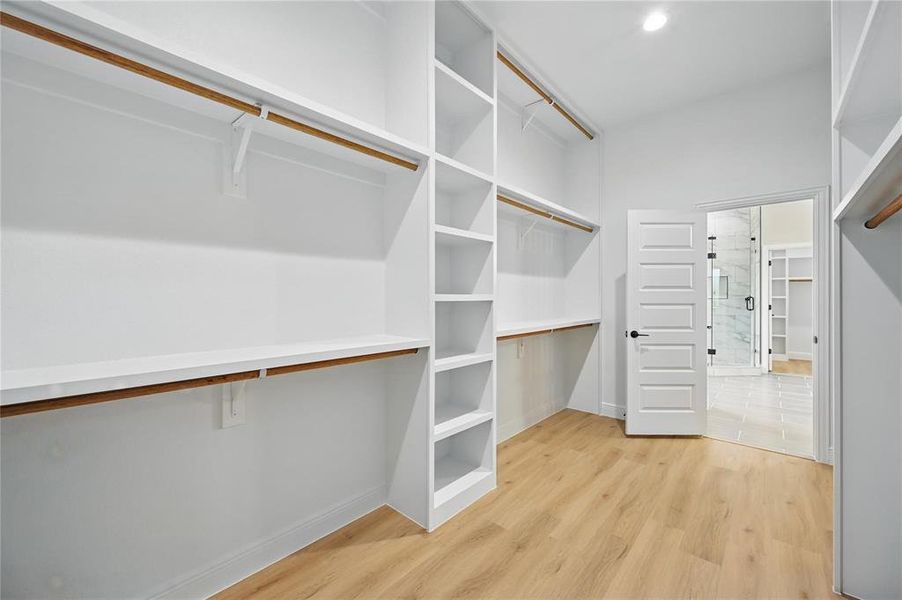 Walk in closet with light wood-style floors Walk in closet with light wood-style floors