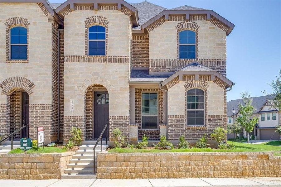 French country home featuring stone siding, brick siding, and a shingled roof French country home featuring stone siding, brick siding, and a shingled roof