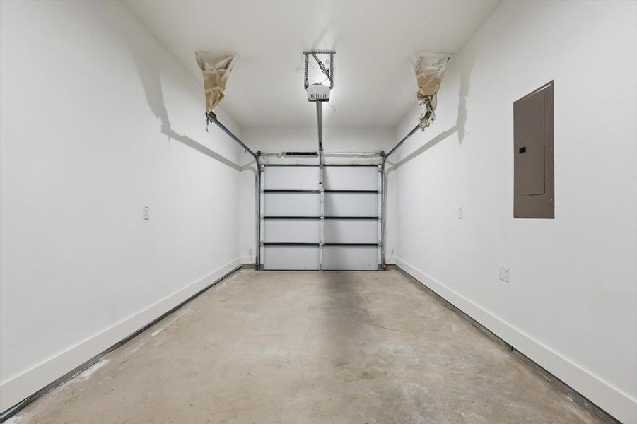 Garage featuring electric panel and baseboards Garage featuring electric panel and baseboards