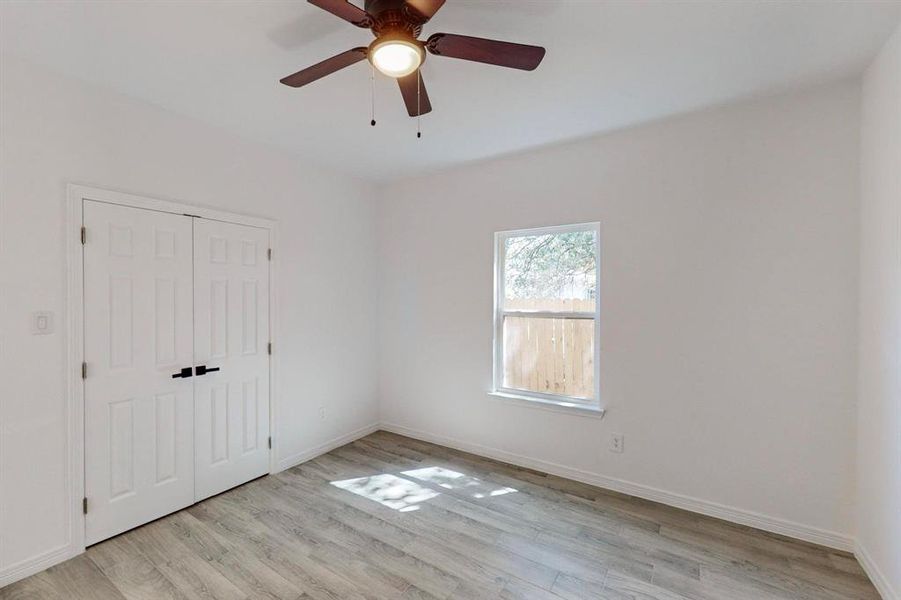 Secondary bedroom room with ceiling fan and light wood-type flooring