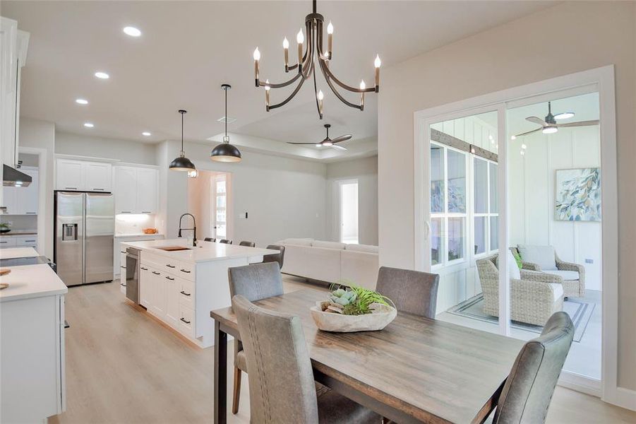 Dining space featuring a ceiling fan, light wood-style flooring, recessed lighting, and a chandelier Dining space featuring a ceiling fan, light wood-style flooring, recessed lighting, and a chandelier