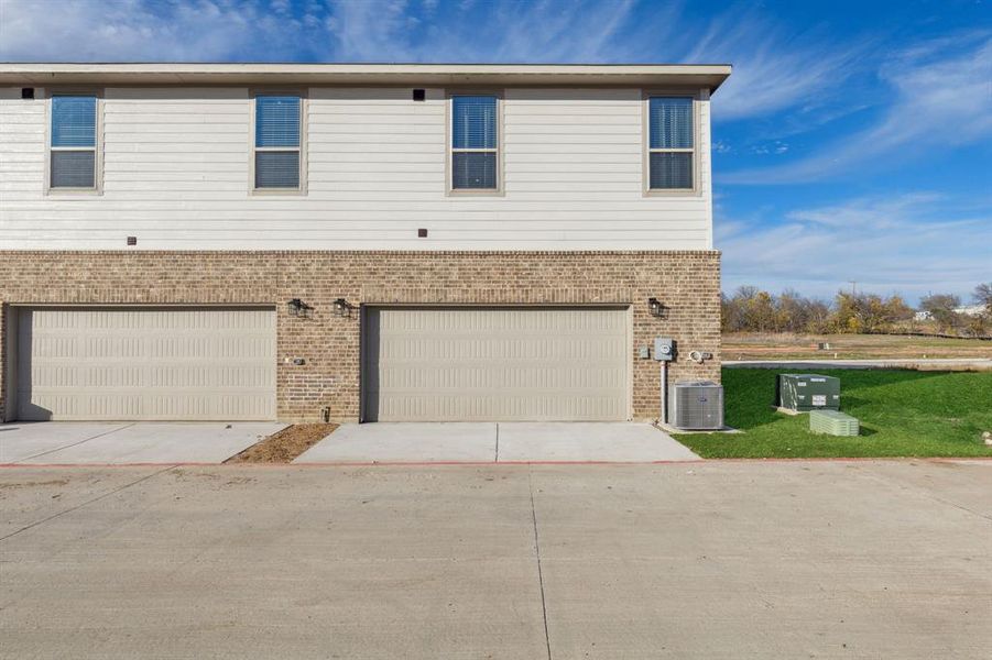 View of front of home with a garage and central air condition unit