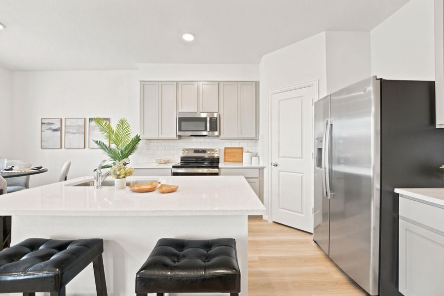 Clean lines and smooth stone countertops define this modern, open kitchen space.