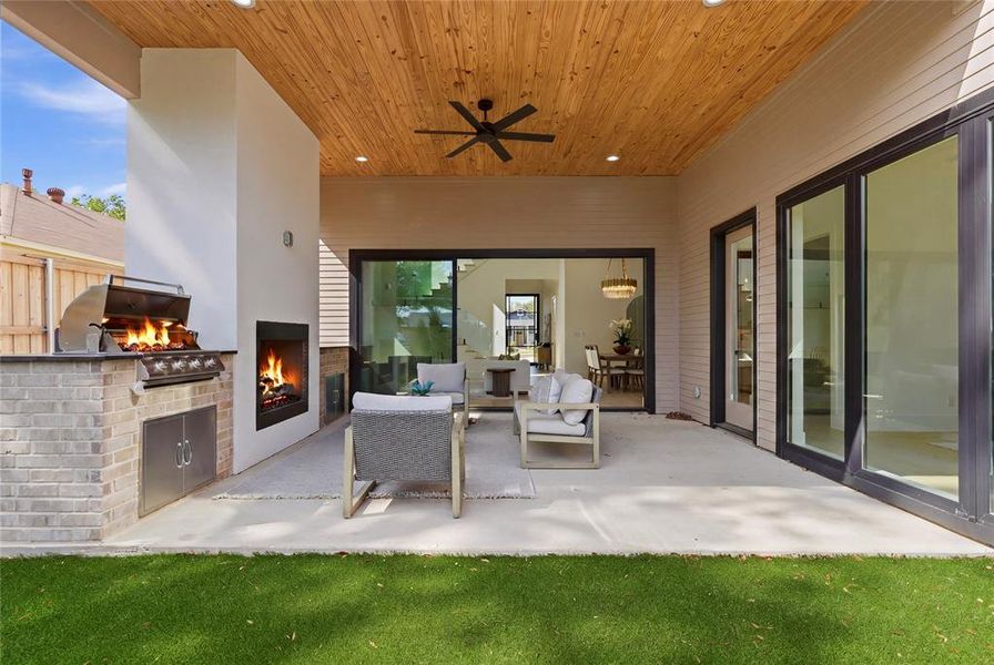 Covered outdoor living space featuring a wood-finish ceiling, built-in fireplace, and an outdoor kitchen with a grill Covered outdoor living space featuring a wood-finish ceiling, built-in fireplace, and an outdoor kitchen with a grill