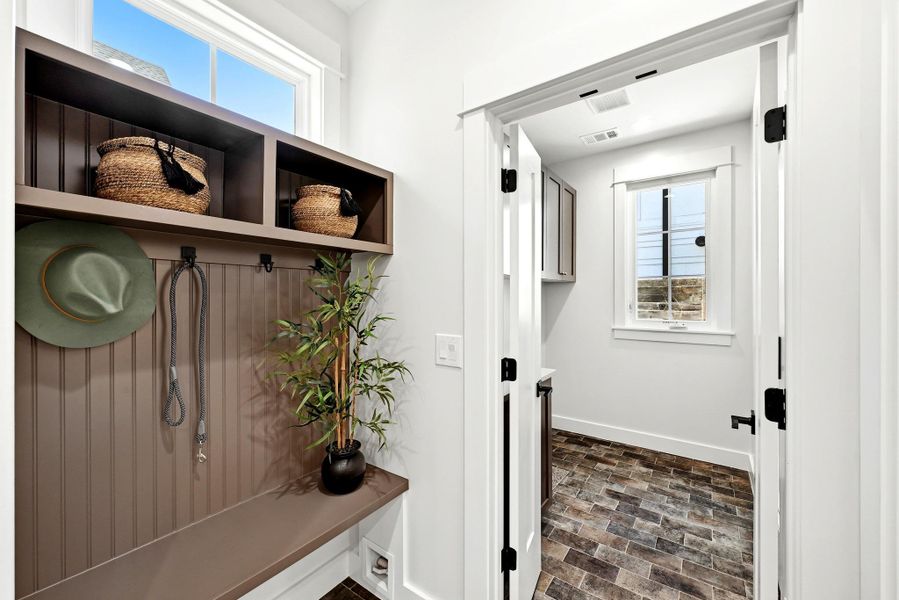 A well-appointed mudroom offers convenient storage solutions, featuring built-in shelving and a bench, leading into a practical laundry area. A well-appointed mudroom offers convenient storage solutions, featuring built-in shelving and a bench, leading into a practical laundry area.