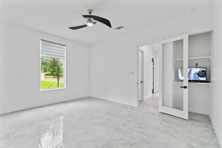 Unfurnished bedroom featuring ceiling fan, light marble finish floors, and french doors