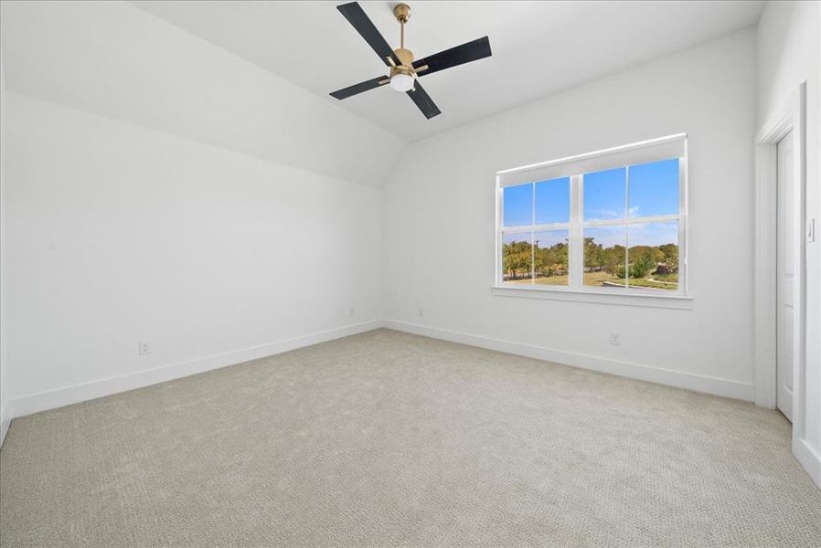 Unfurnished bedroom featuring baseboards, ceiling fan, lofted ceiling, and light colored carpet