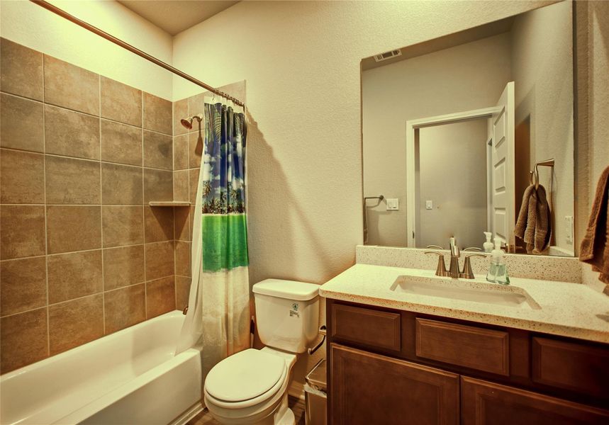 Full bath featuring a textured wall, vanity, and shower / bathtub combination with curtain Full bath featuring a textured wall, vanity, and shower / bathtub combination with curtain