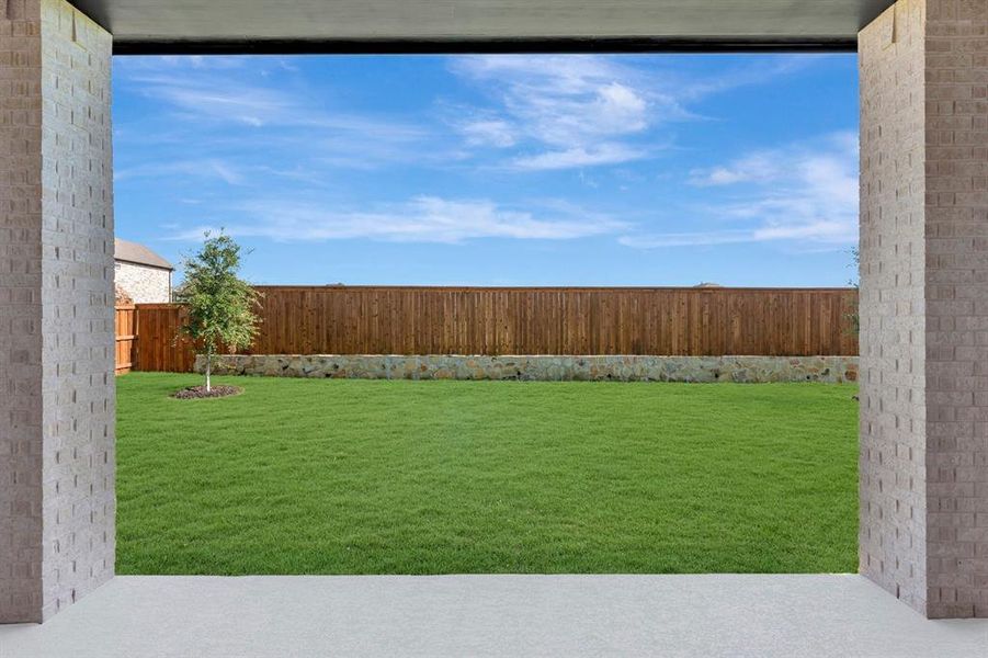 Expansive green lawn framed by a stone retaining wall and a wood fence Expansive green lawn framed by a stone retaining wall and a wood fence