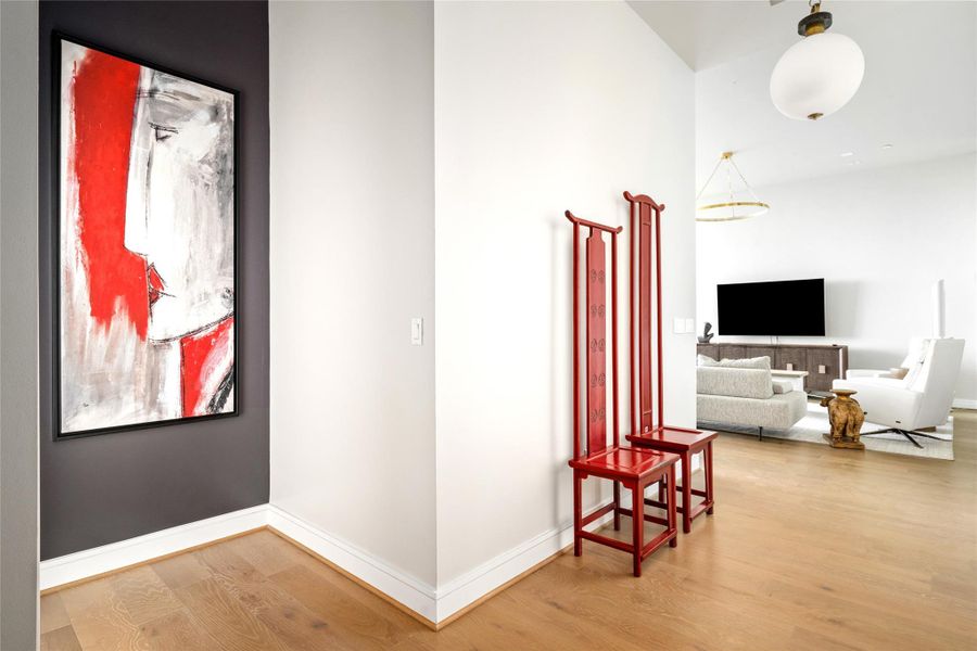 A striking red artwork energizes the space, perfectly paired with a sleek red coat rack for a cohesive pop of color.