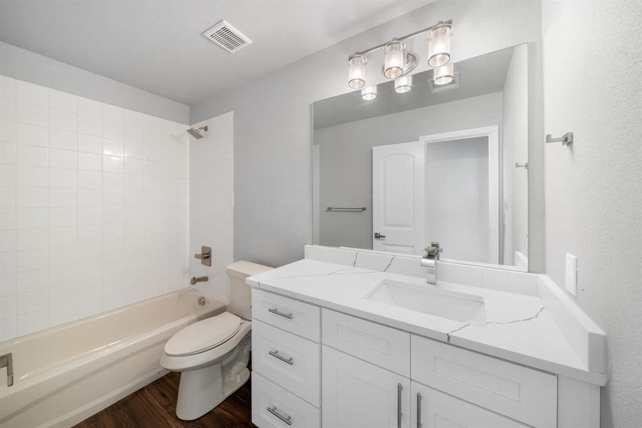 Full bathroom featuring hardwood / wood-style flooring, toilet, vanity, and tiled shower / bath