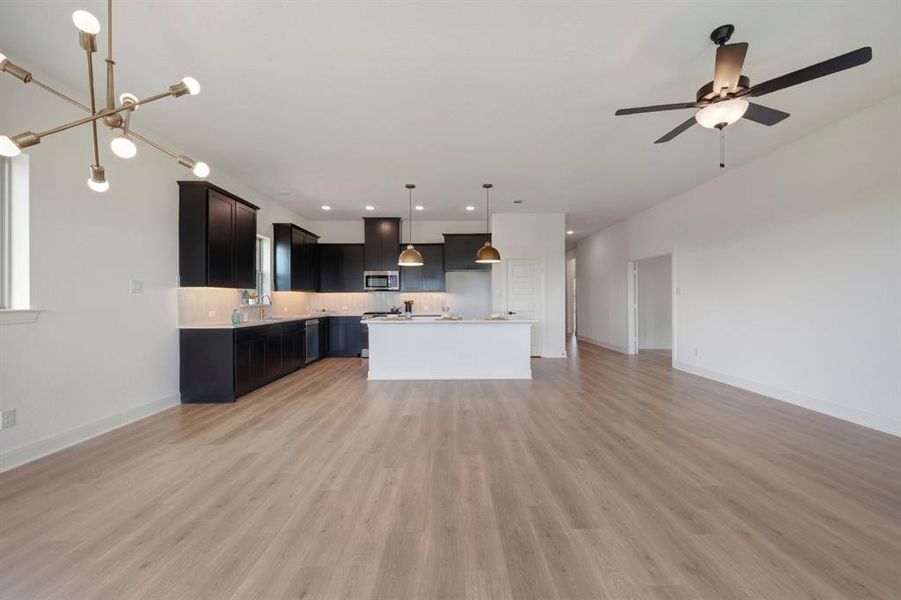 Kitchen with open floor plan, light countertops, a kitchen island with sink, tasteful backsplash, and ceiling fan Kitchen with open floor plan, light countertops, a kitchen island with sink, tasteful backsplash, and ceiling fan