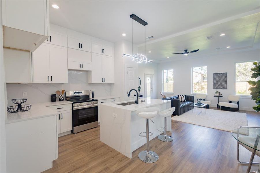 Kitchen with hanging light fixtures, stainless steel range with electric cooktop, white cabinets, light stone counters, and recessed lighting Kitchen with hanging light fixtures, stainless steel range with electric cooktop, white cabinets, light stone counters, and recessed lighting