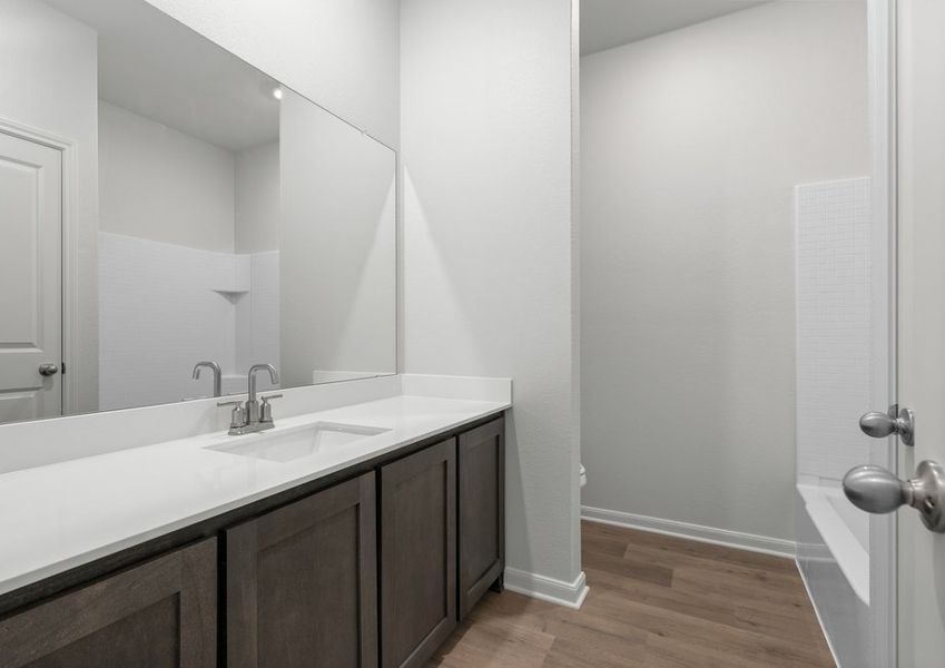 The secondary bathroom has a large vanity space and a shower-tub combo.