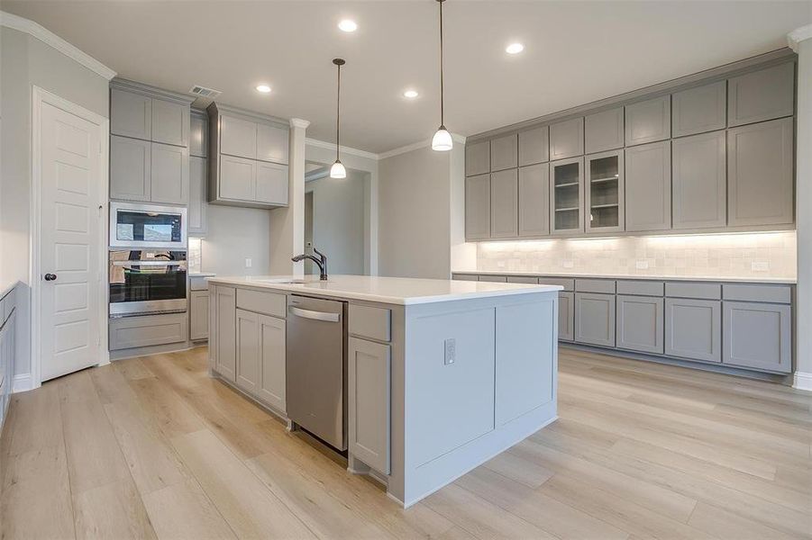 Kitchen featuring crown molding, stainless steel appliances, light hardwood / wood-style flooring, and gray cabinetry