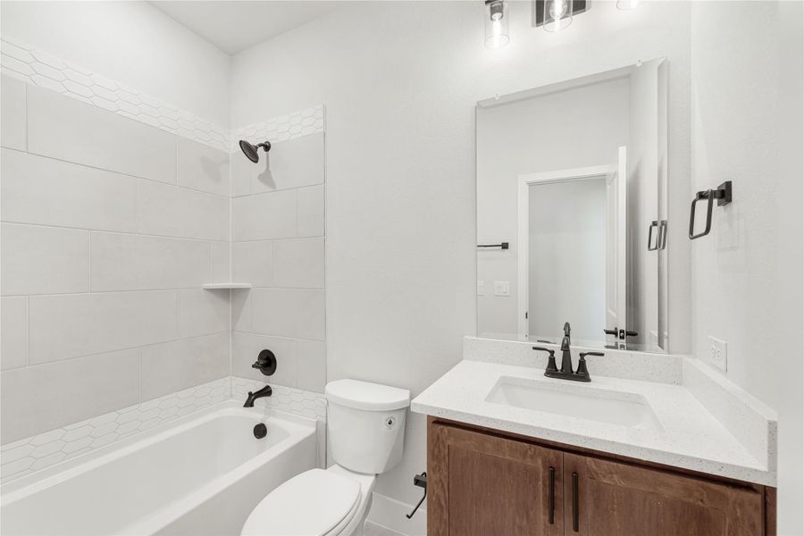 Bathroom with tiled tub-shower combo, wood vanity with quartz countertop, and matte black fixtures Bathroom with tiled tub-shower combo, wood vanity with quartz countertop, and matte black fixtures