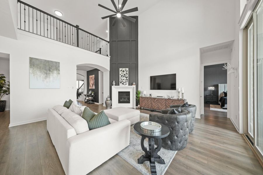 The soaring 20-foot ceiling in the family room creates an atmosphere of elegance featuring a gas log fireplace with cast stone surround and mantel, decorative trim that stretches from the mantle to the ceiling and a ceiling fan with an integrated light.