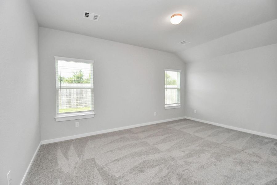 Escape to tranquility in this spacious primary room, adorned with plush carpeting and bathed in the soothing hues of warm paint colors, creating a cozy retreat for relaxation.