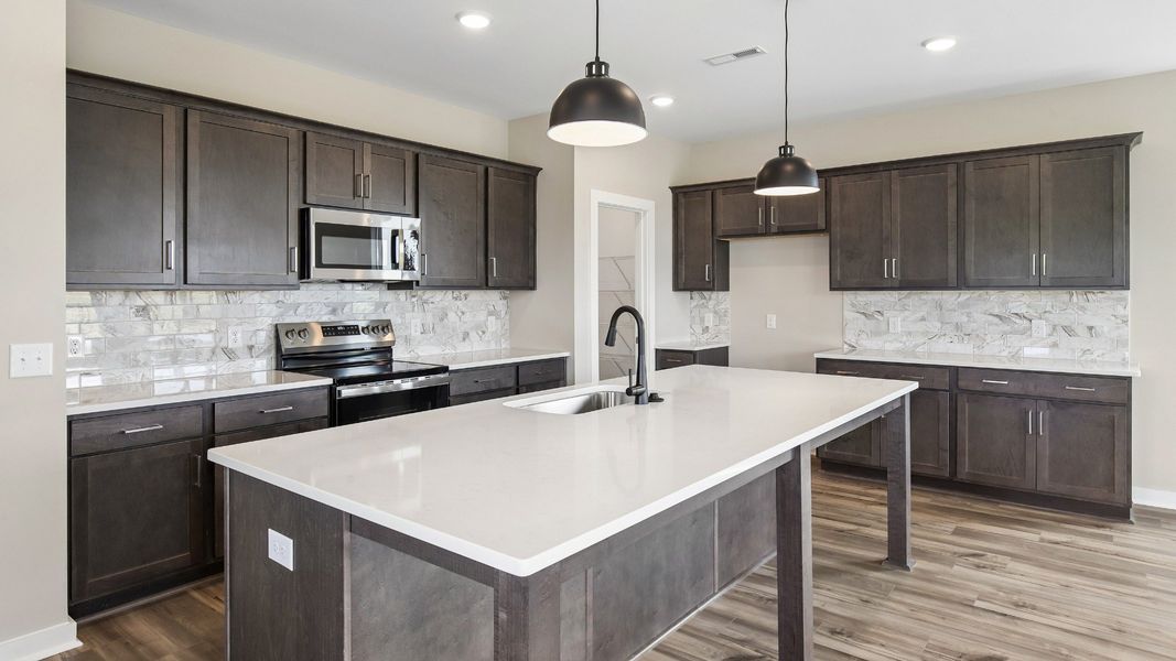 Kitchen with dark cabinetry, quartz countertops, and tile backsplash